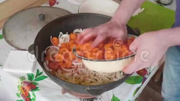 白色厨师的手加入切胡萝卜并在洋葱上传播同时烹饪圆顶视频的预览图