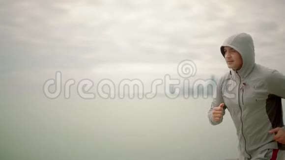 一个年轻的运动员在城市和湖泊的背景下奔跑慢动作视频的预览图