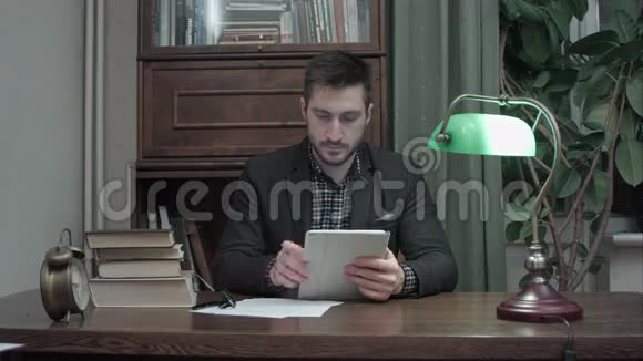 男性研究人员使用数字平板电脑坐在他的办公桌上做笔记视频的预览图