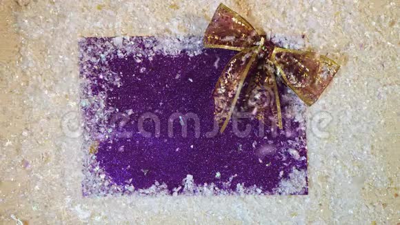 在紫色背景上用丝带的蝴蝶结观看降雪视频的预览图
