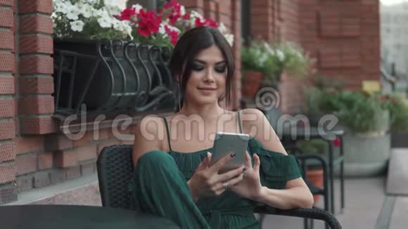 在老城迷人的女孩坐在户外的咖啡馆里用手机年轻女子用智能手机发信息视频的预览图