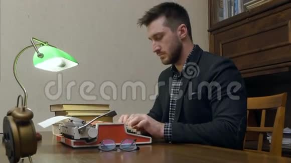 聚焦的记者用打字机打着一篇文章坐在办公桌前用绿色的灯视频的预览图