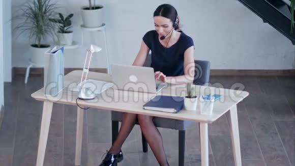 快乐迷人的年轻女性坐在办公室里用手提电脑工作视频的预览图