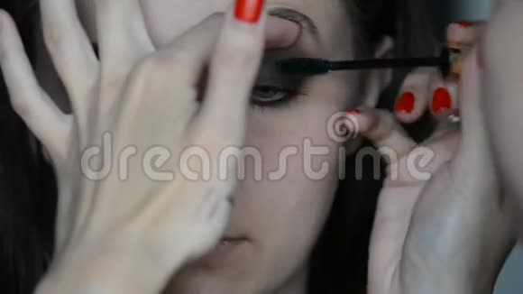 特写化妆师在模特儿的眼睛和眉毛上化妆绿色文印上一个红色成熟番茄的化妆马克罗形象视频的预览图