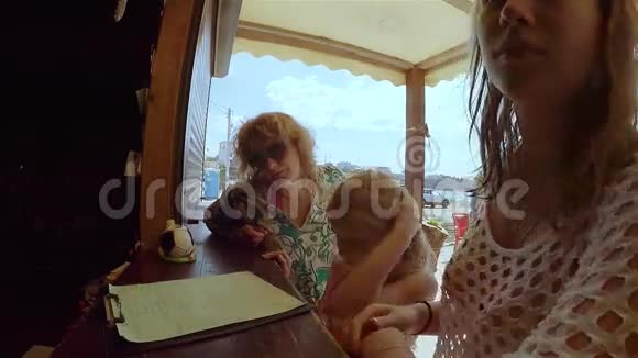 妈妈和两个女儿选择在海滩咖啡馆吃早餐视频的预览图