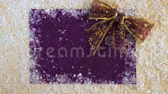 在紫色背景上用丝带的蝴蝶结观看降雪视频的预览图
