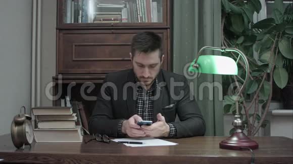 年轻人坐在书房的桌子上拿着书用手机视频的预览图