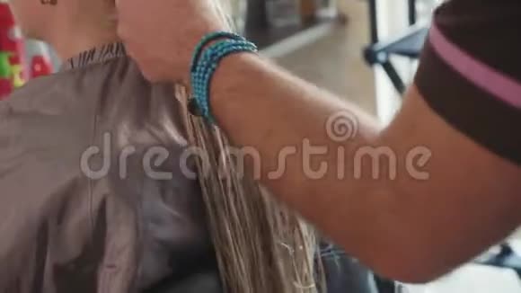 在美容院的男理发师给金发女郎梳头特写视频的预览图