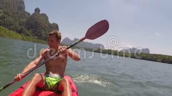 男子划艇在美丽的泻湖动作相机年轻人在皮划艇上划艇视频的预览图