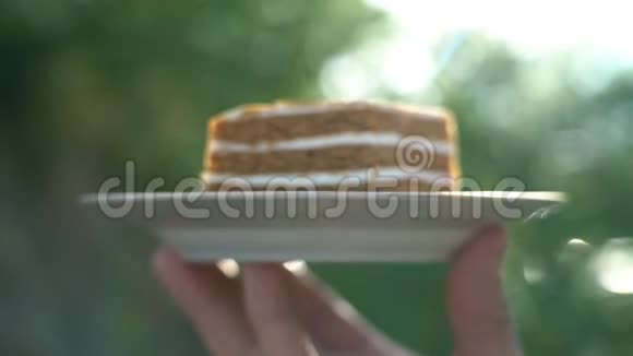 男人手里拿着一块蛋糕在绿色的背景下阳光阳光甜蜜的牙齿贪婪的激情视频的预览图
