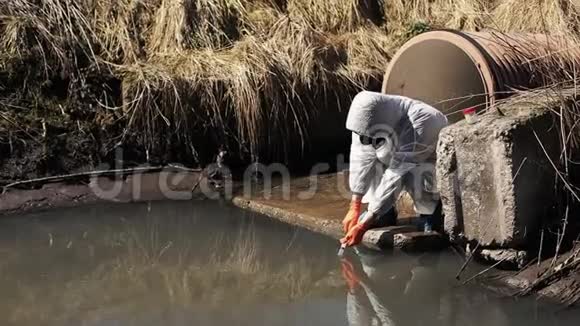 穿着生物危险服和防毒面具的人检查外面的水污染视频的预览图