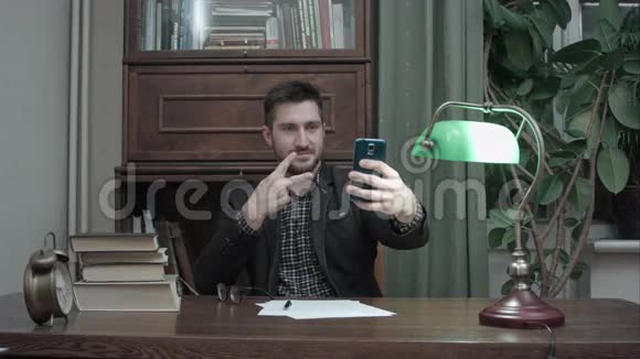 年轻人坐在办公桌前用手机自拍视频的预览图