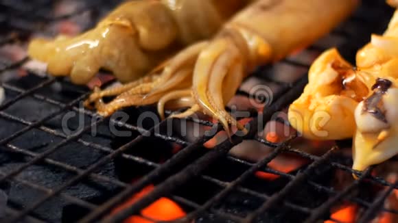夜市芭堤雅宗甸鱿鱼烤在烤架上泰国菜市场上的亚洲异国菜肴视频的预览图