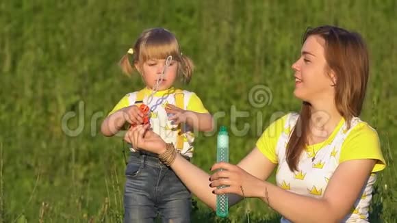 快乐的孩子在夏天的公园里吹肥皂泡慢动作视频的预览图