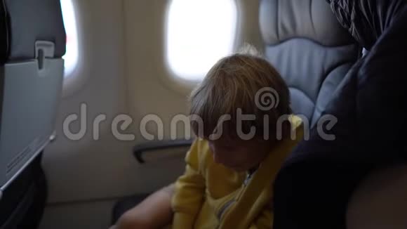 一个小男孩坐在飞机上的椅子上玩白色玩具飞机的慢镜头自由视频的预览图