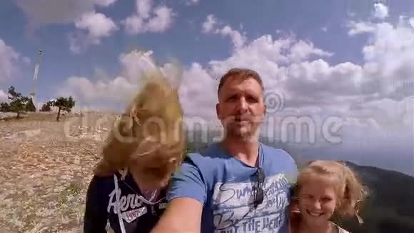 爸爸和两个女儿从山顶拍自拍视频每个人都笑着偷窥视频的预览图