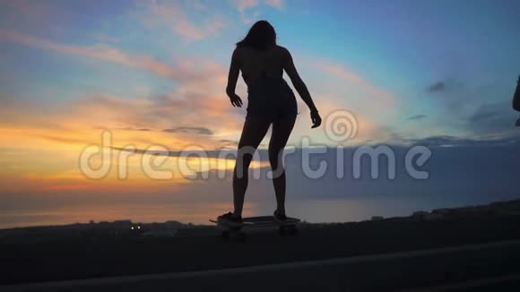 两个女孩在天空和阳光下的滑板轮廓视频的预览图