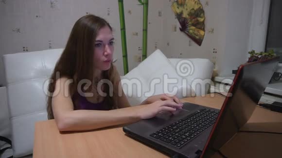 年轻漂亮的女人在家里兴高采烈地在笔记本电脑上打字视频的预览图
