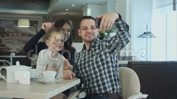 美丽的年轻家庭自拍在Smartfone同时享受他们的时间在咖啡馆视频的预览图