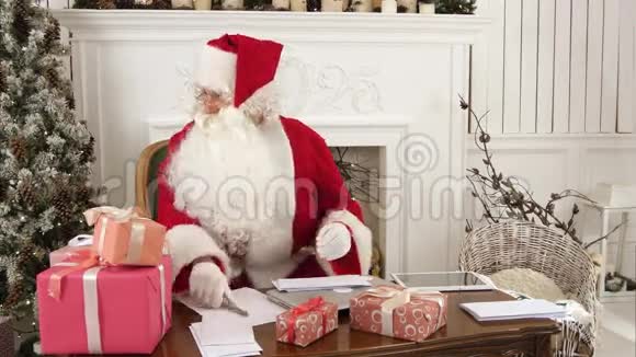 忙忙碌碌的圣诞老人给孩子们信件而可爱的小帮手给他送礼物视频的预览图