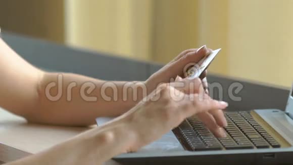 特写女人手拿着信用卡用电脑键盘进行网上购物视频的预览图