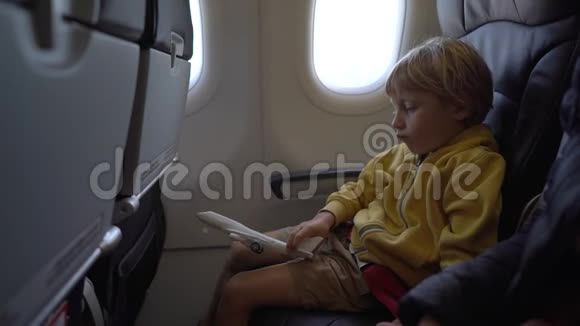 一个小男孩坐在飞机上的椅子上玩白色玩具飞机的慢镜头自由视频的预览图