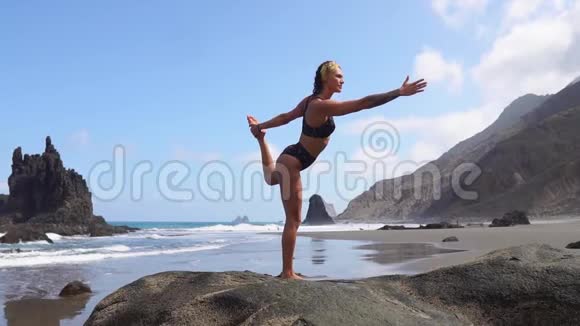 一条腿站在石头上做瑜伽平衡的女孩心灵的平静健康生活方式视频的预览图