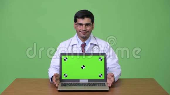 年轻英俊的波斯医生带着笔记本电脑视频的预览图