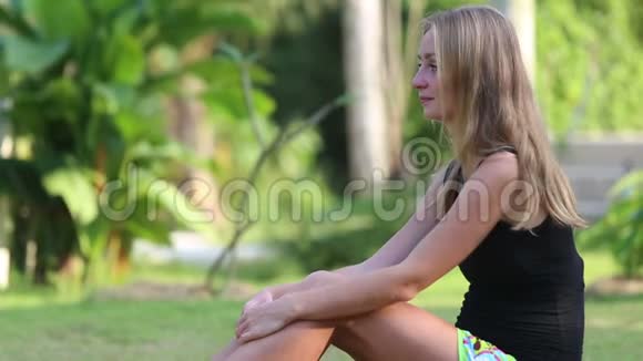 年轻的金发女人坐在草地上视频的预览图