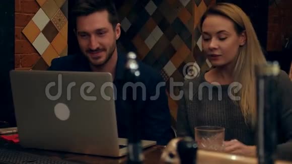 一对夫妇通过笔记本电脑与餐馆里的朋友进行视频聊天视频的预览图