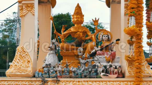在花园里的一个供祈祷的金色佛教小祭坛上面装饰着鲜花和各种雕像视频的预览图