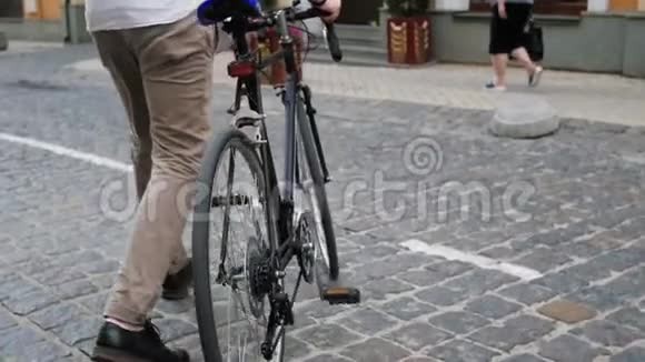 慢动作低角度视频年轻人坐在老式自行车和骑在铺好的道路上视频的预览图