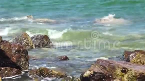 海浪溅到多石的海滩上波涛拍打岩石海滩蓝色海水和大石头背景视频的预览图