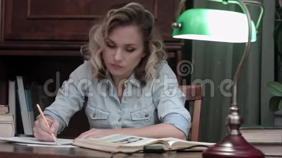 年轻女子做最后的笔记从桌子上收集文件和书籍然后离开视频的预览图