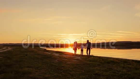 幸福的一家人在日落时在水边散步视频的预览图