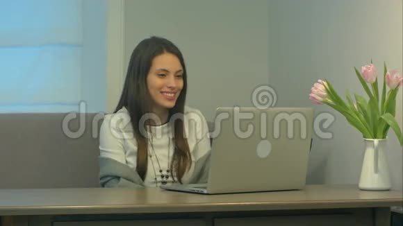 穿着白色衣服的漂亮黑发女人在玩手提电脑的视频游戏时说话很严肃视频的预览图