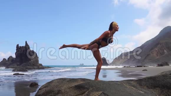 一条腿站在石头上做瑜伽平衡的女孩心灵的平静健康的生活方式平衡与和谐视频的预览图