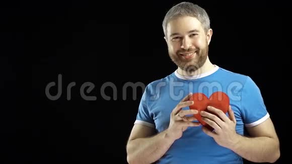 戴着蓝色t恤的满脸胡须的男人红心爱情浪漫约会求婚的概念黑色背景视频的预览图