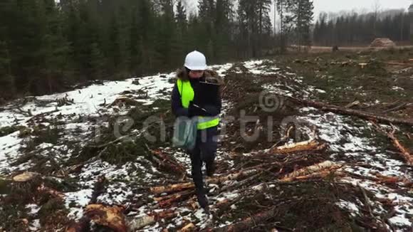 女林业检查员在砍伐的树木之间行走视频的预览图