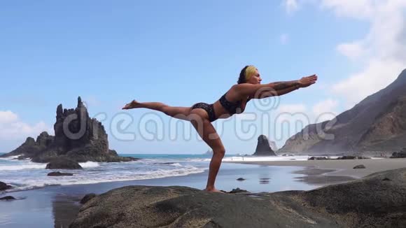 一条腿站在石头上做瑜伽平衡的女孩心灵的平静健康的生活方式平衡与和谐和平视频的预览图
