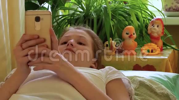 女孩用智能手机躺在床上视频的预览图