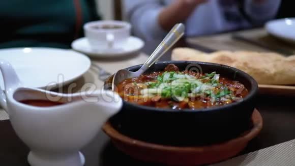 餐厅Ketsi的格鲁吉亚肉盘查舒舒利餐桌上的泥锅热肉视频的预览图