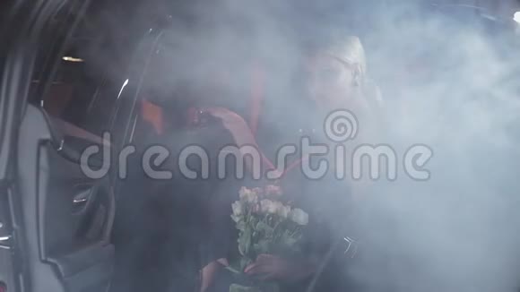 一个漂亮的金发碧眼带着白玫瑰从黑色的车里出来视频的预览图
