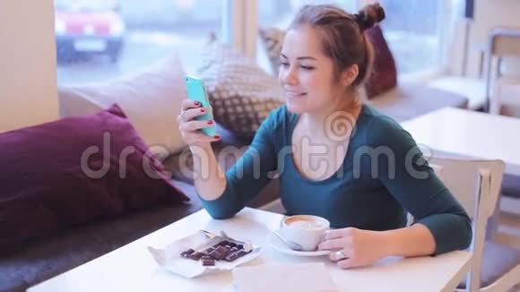 咖啡馆里的女孩在视频聊天在你的智能手机上看有趣的视频视频的预览图