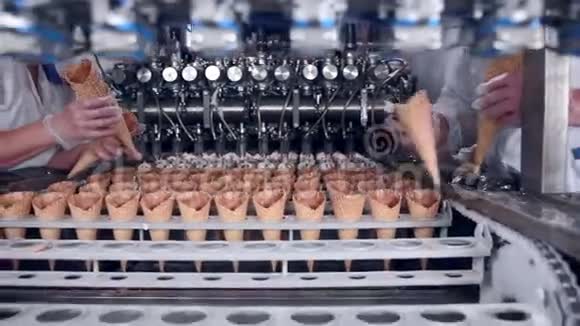 移动皮带与冰淇淋锥和工人的手放他们食品工业视频的预览图