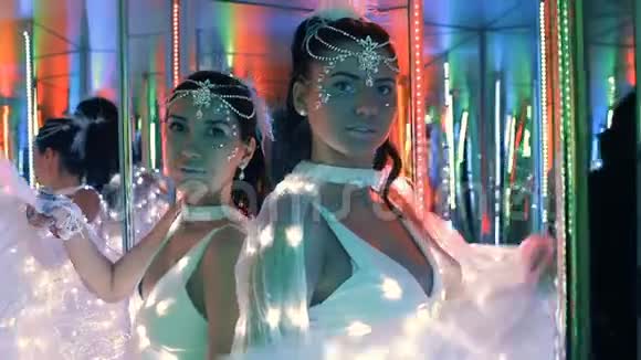 两个穿着白色发光二极管的深色女人在镜子里视频的预览图