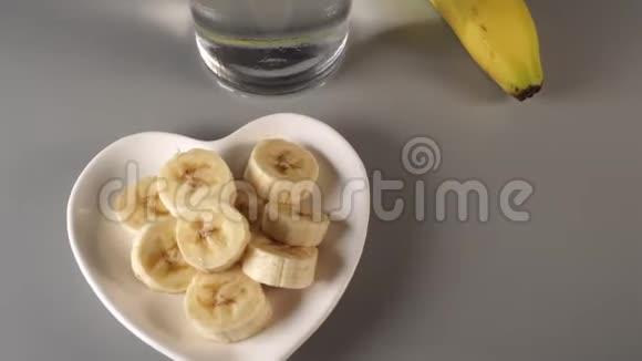 切片和整根香蕉在白色的盘子上在灰色背景下视频的预览图