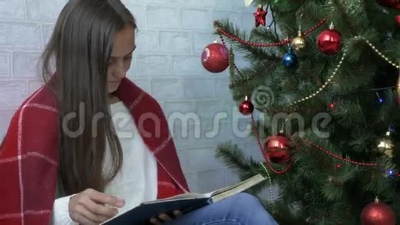 圣诞树附近的漂亮女人读书视频的预览图