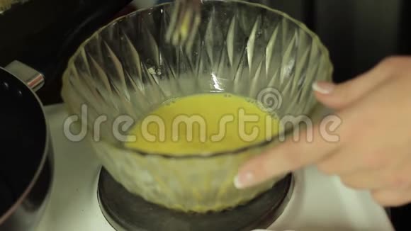 女人用玻璃盘子在厨房里搅拌鸡蛋视频的预览图