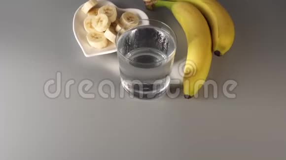 切片和整根香蕉在白色的盘子上在灰色背景下视频的预览图